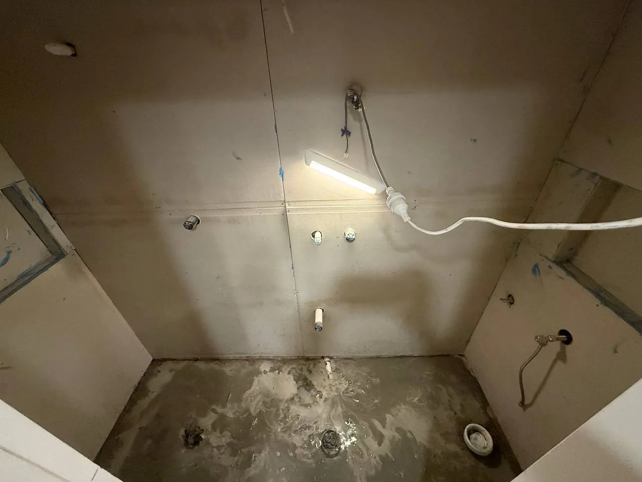 Bathroom wall sheeting installed with plumbing outlets exposed
