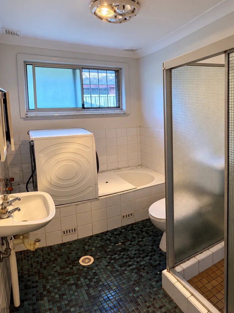 Before renovation: original bathroom with mosaic floor tiles, bath, basin and enclosed shower