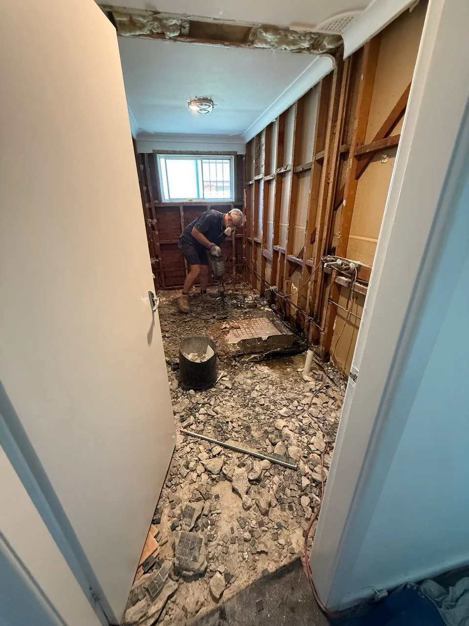 Worker breaking out the original bathroom floor during demolition