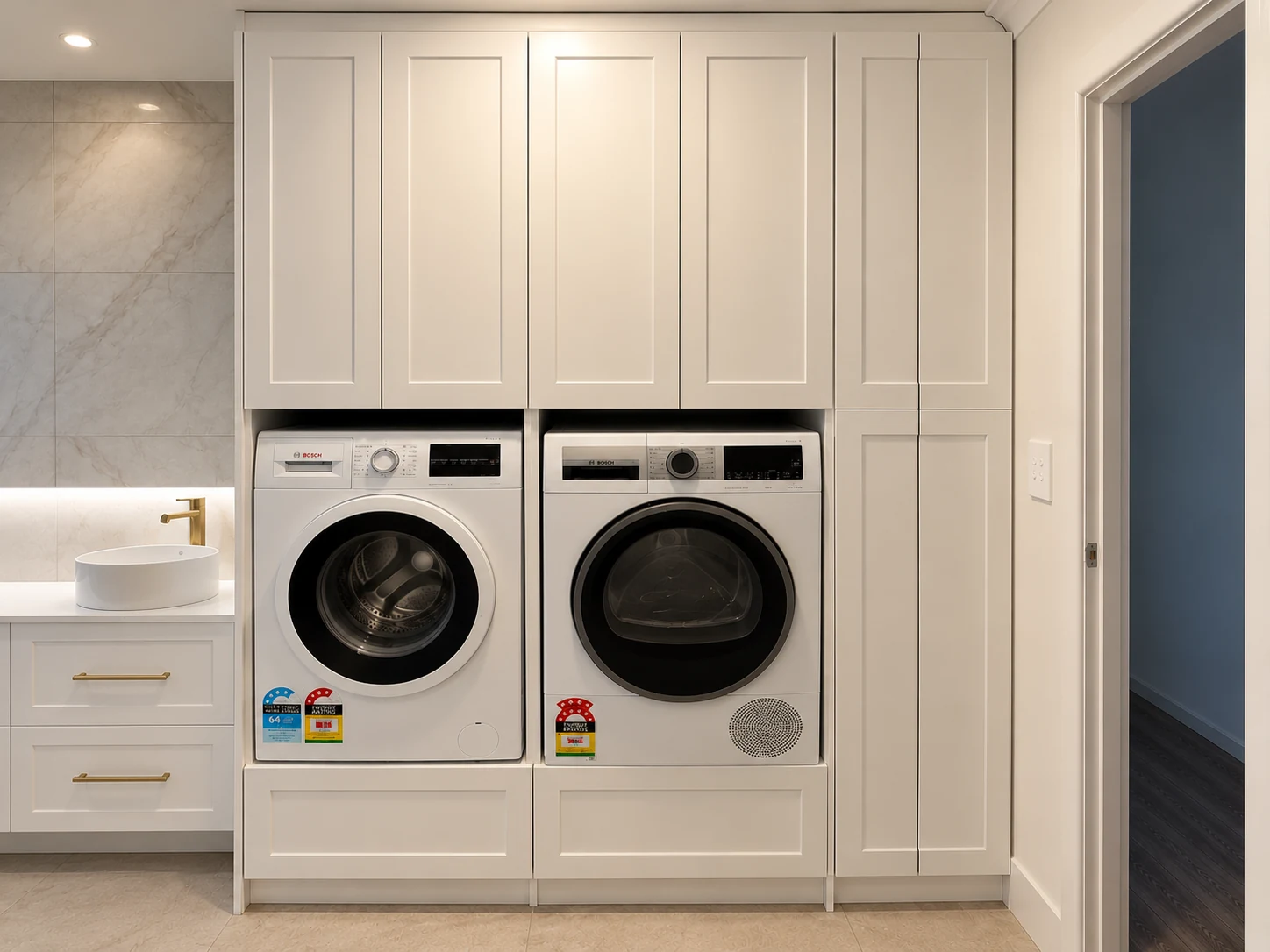 Completed Hillsdale laundry with custom white cabinetry and integrated washing machine and dryer