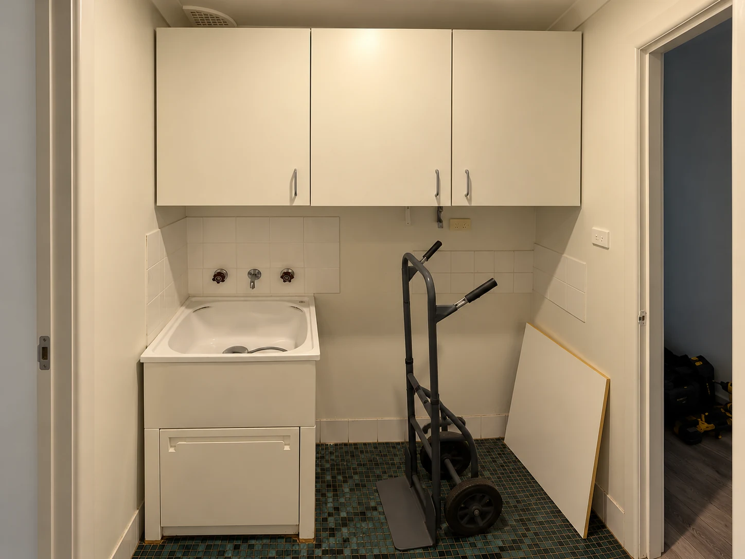 Original Hillsdale laundry with older white cabinets and dark mosaic tile flooring