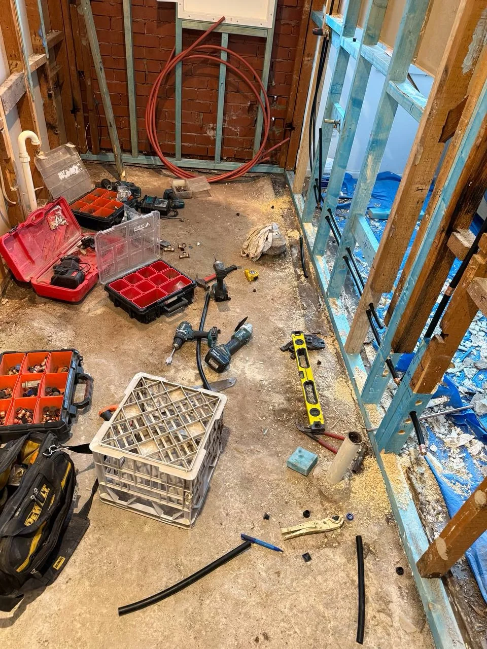 Laundry stripped back to exposed wall framing, brickwork and plumbing, with tools on site