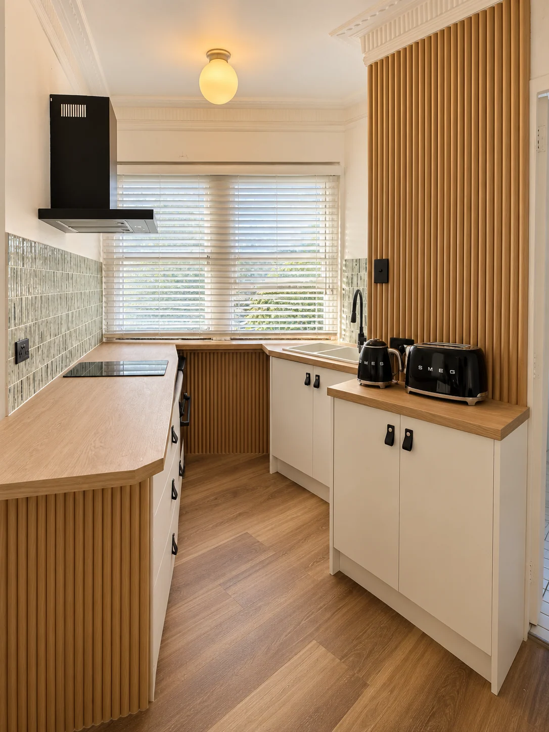Completed Potts Point galley kitchen with wood-look benchtops, vertical timber battens, modern white cabinetry and black fittings