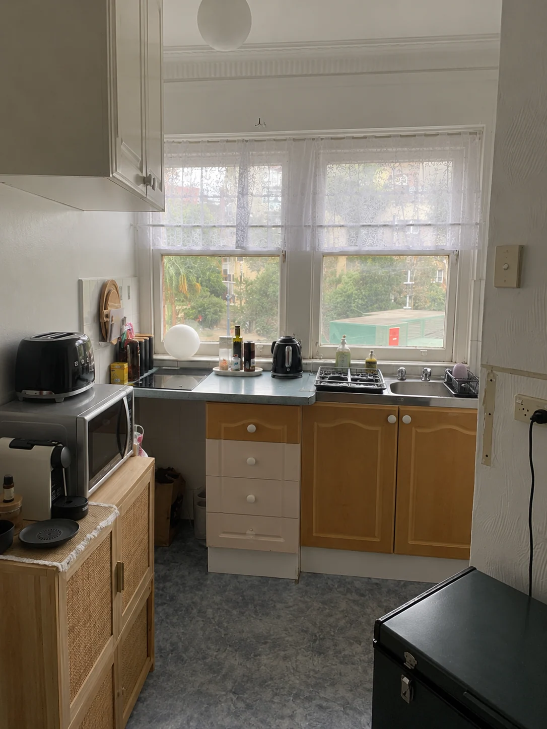 Potts Point kitchen before renovation with older timber doors, pale blue benchtop, venetian window blinds and grey vinyl floor