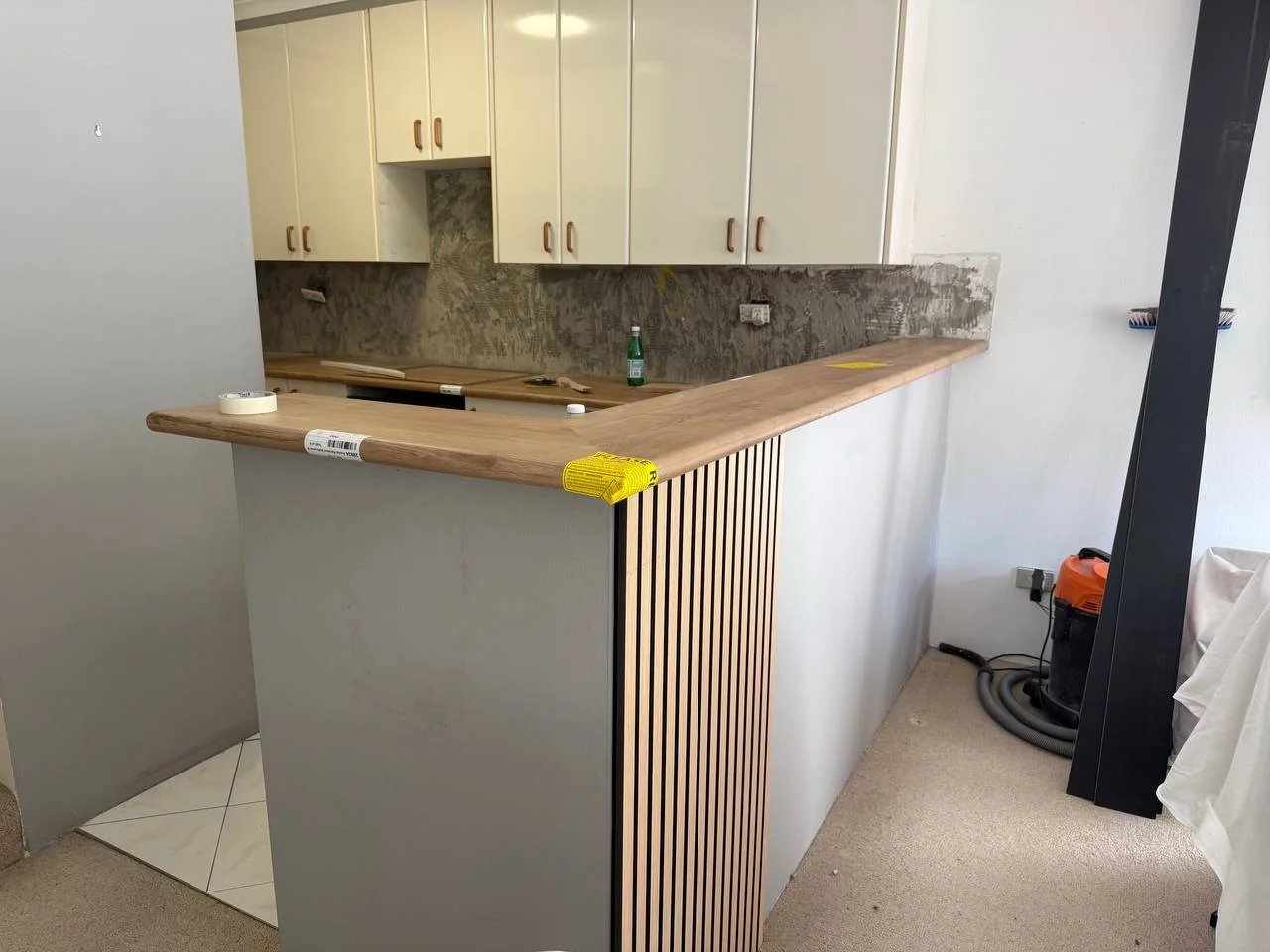 Timber-look breakfast bar benchtop and vertical slat feature being installed