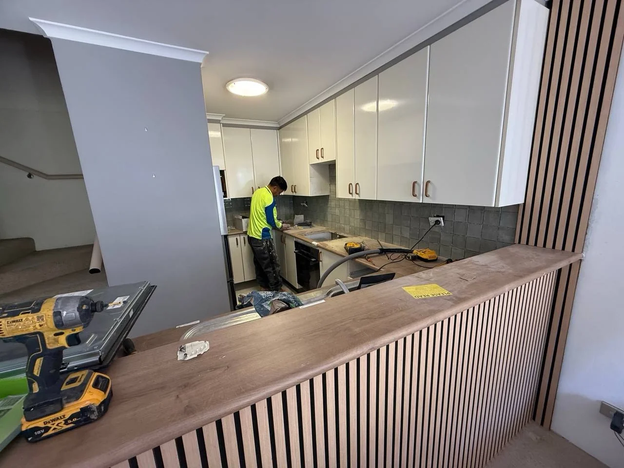 Tradesperson finishing kitchen splashback with new breakfast bar detailing